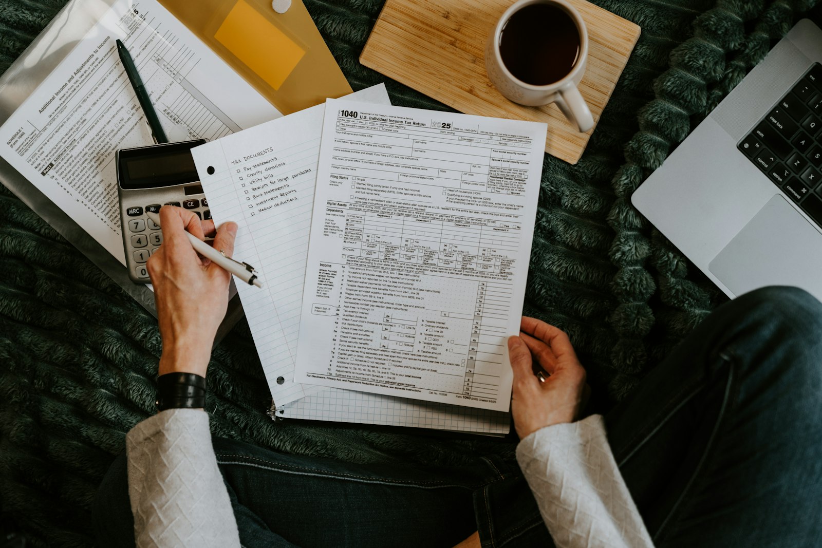 Person reviewing tax documents with a calculator and laptop