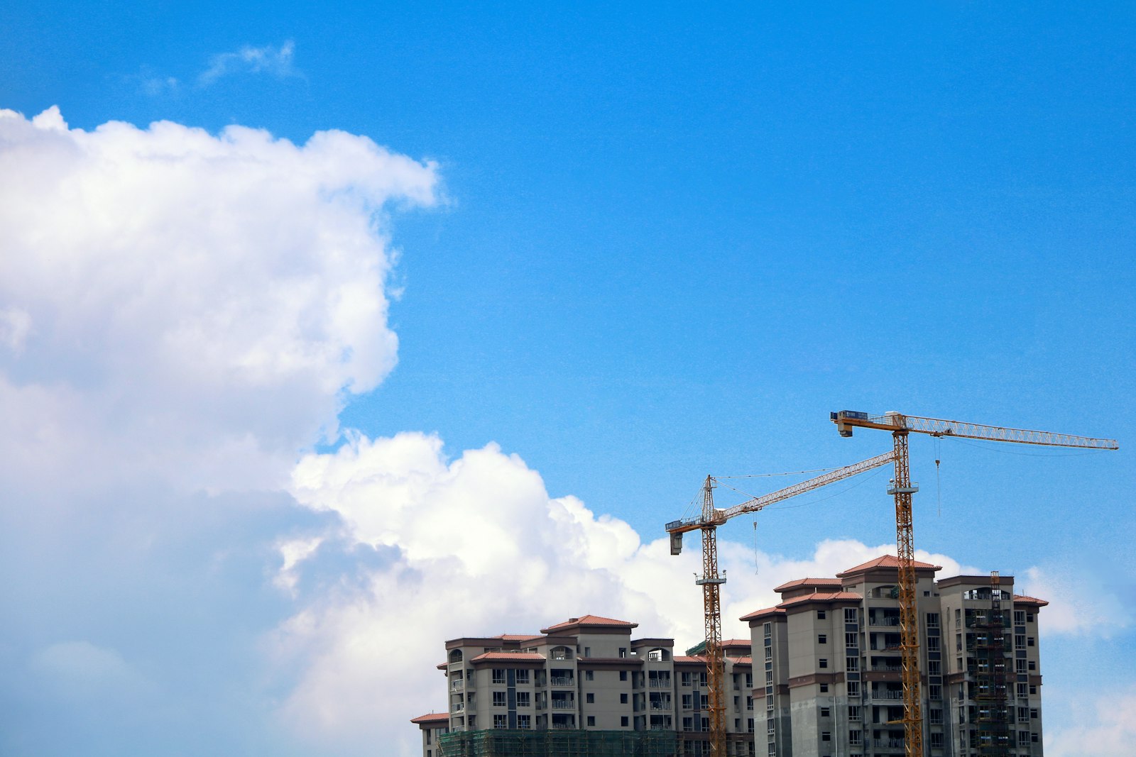 Residential buildings under construction beneath cranes